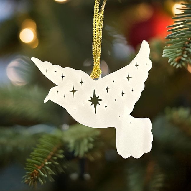 White peace dove ornament with star cutouts hanging on a Christmas tree