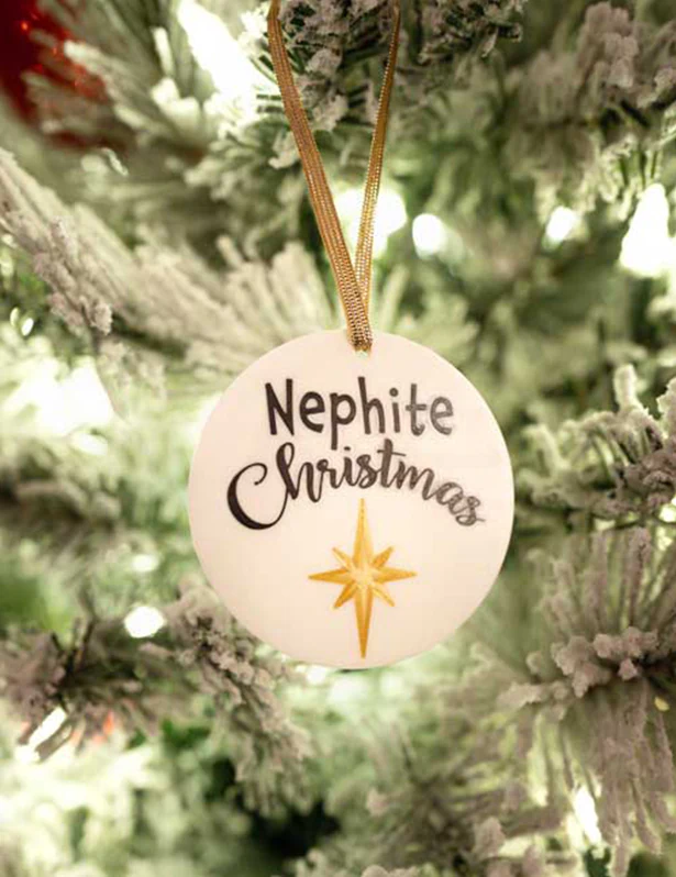 Round white Nephite Christmas ornament with a gold star hanging on a Christmas tree